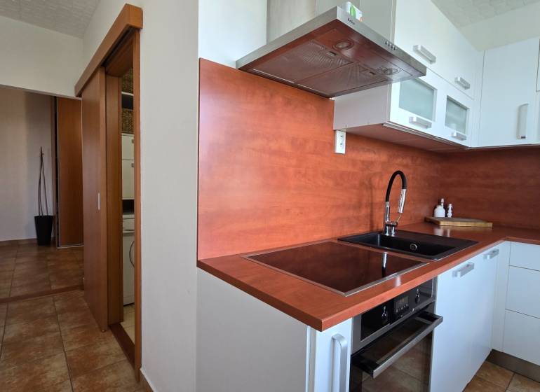 A kitchen in a 2-room apartment with built-in appliances and modern cabinets.