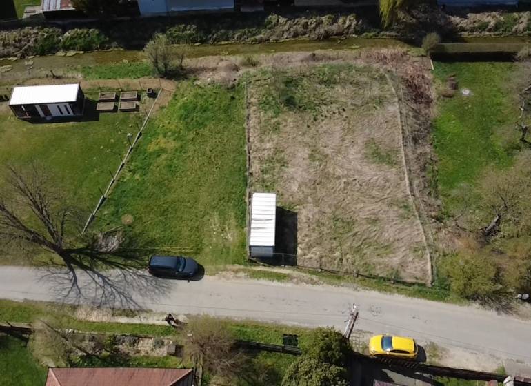 Aerial view of a street with a plot of land, a utility building, and two cars, ideal for living.