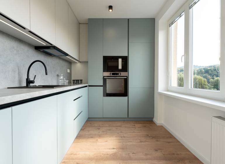 A bright kitchen in a 2-room apartment with modern appliances and a large window.