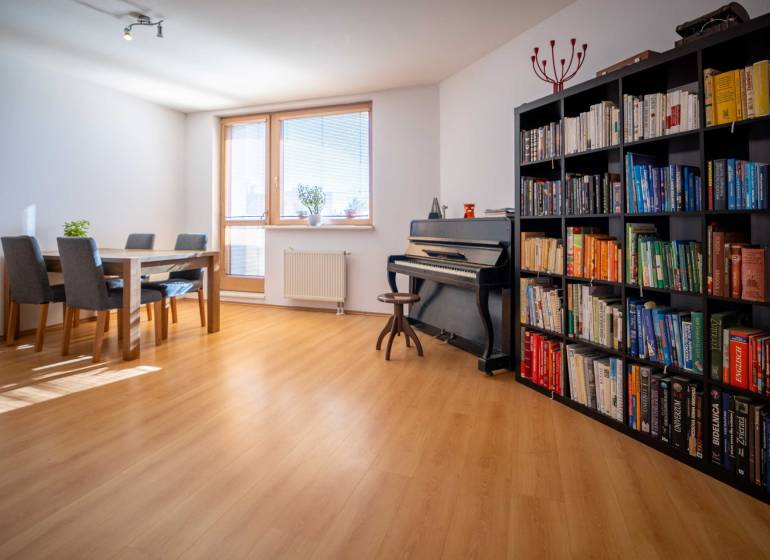 Living room with a piano, bookshelf, table, and chairs in a 3-room apartment.