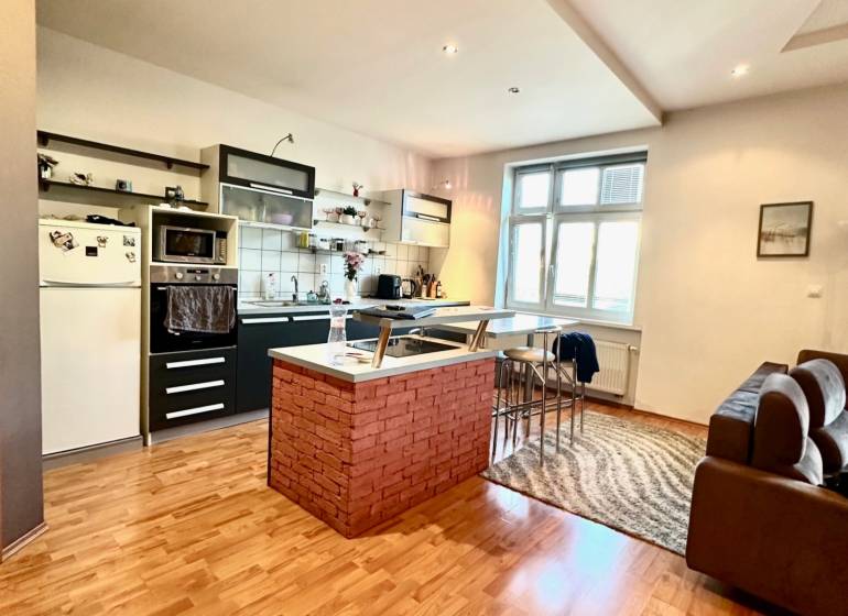 A kitchen with a bar counter and wooden flooring in a 2-room apartment.