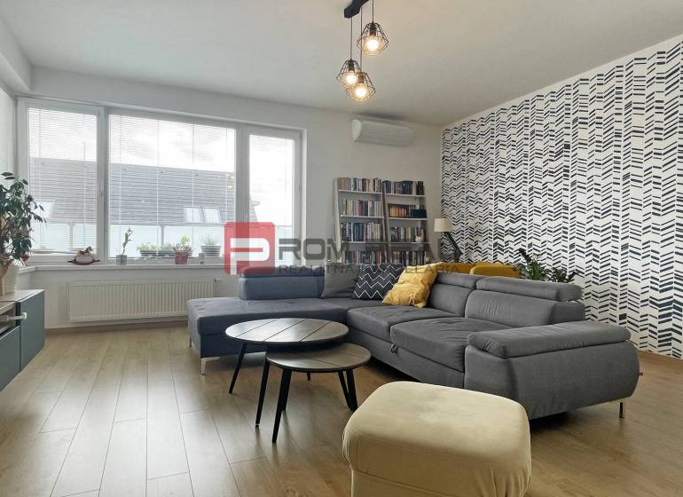 Living room in a two-room apartment with a comfortable sofa, patterned wall, and bookshelf.