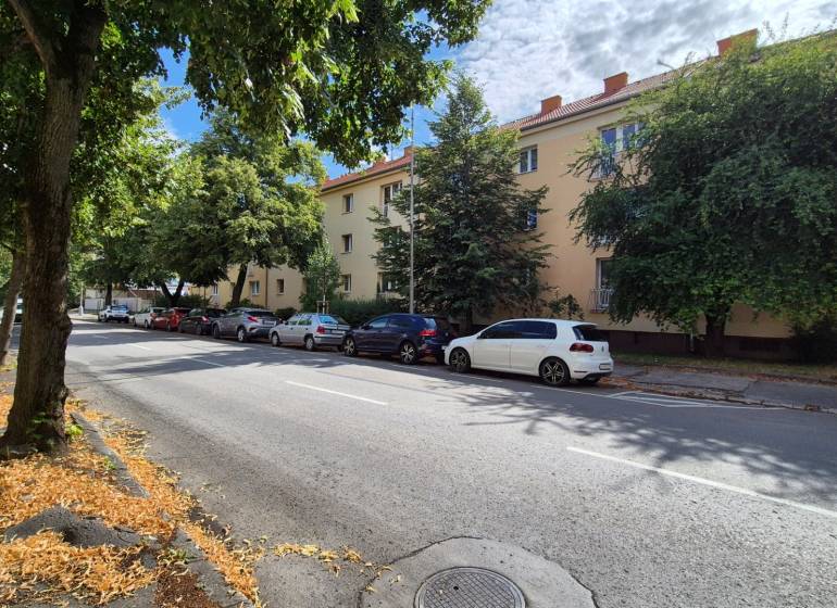 Under Párovce in Piešťany, there are trees lining the road by the three-story apartment buildings.