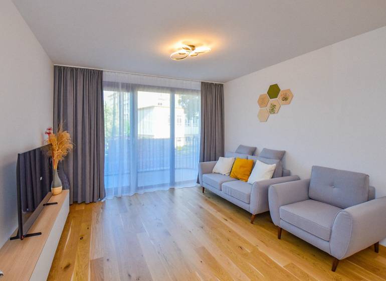 Living room with a comfortable sofa, wooden floor, and a television in a 3-room apartment.