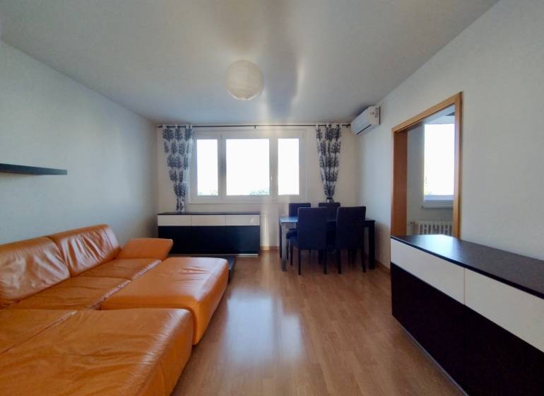 Living room in a three-room apartment with an orange sofa and a wooden decor floor.