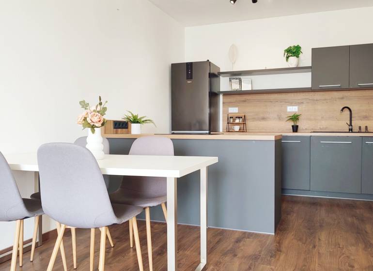 Kitchen with dining table and chairs, 2-room apartment with wooden flooring and decoration.