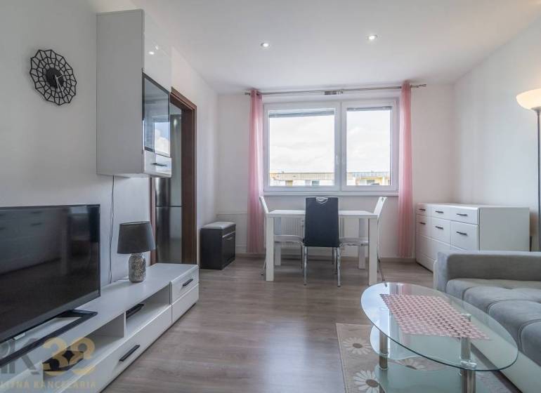 A bright living room with a table, television, and sofa in a three-room apartment.