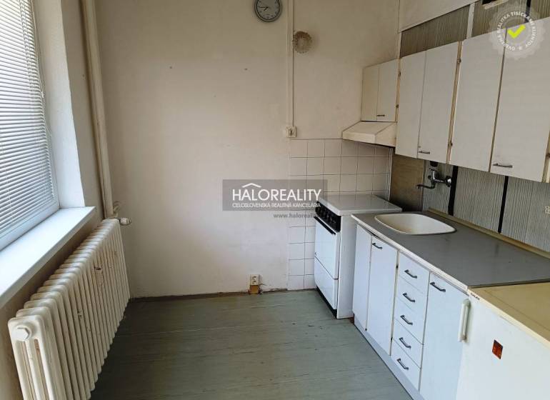 A kitchen in a studio apartment with a stove, sink, and kitchen cabinets.