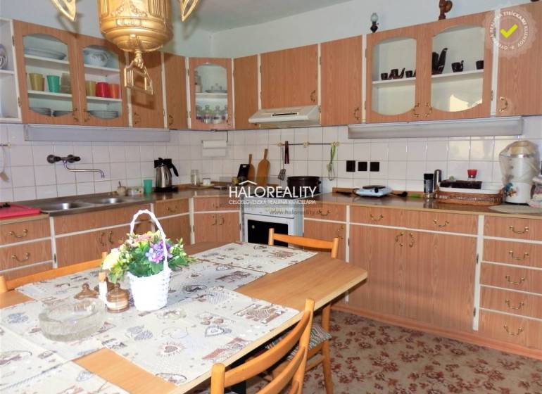 A kitchen in a family house with a wooden cabinet, a dining table, and floral decoration.
