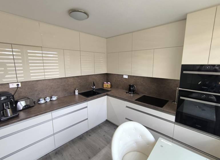 Kitchen in a 3-room apartment, modern cabinets and appliances, light shades.