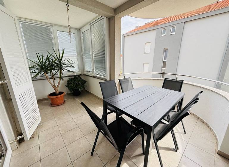 The balcony of a 3-room apartment in Novalja, with flowers and garden furniture on the tiles.