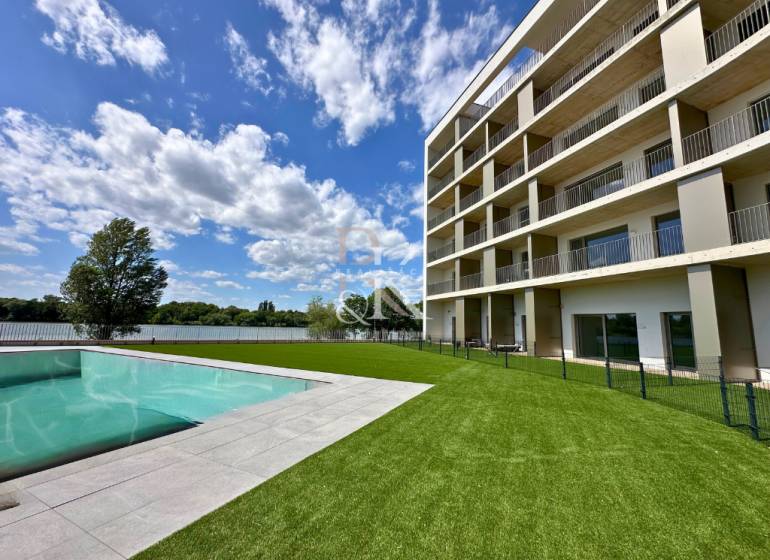 A building with a pool and landscaped lawn by the water in Banka, an ideal location.