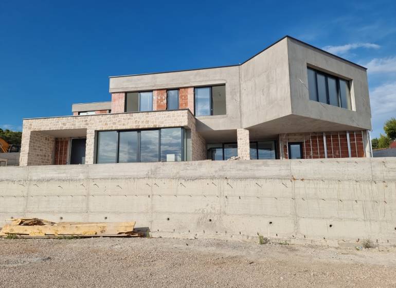 The exterior of the villa in Vodice with modern windows and raw concrete.