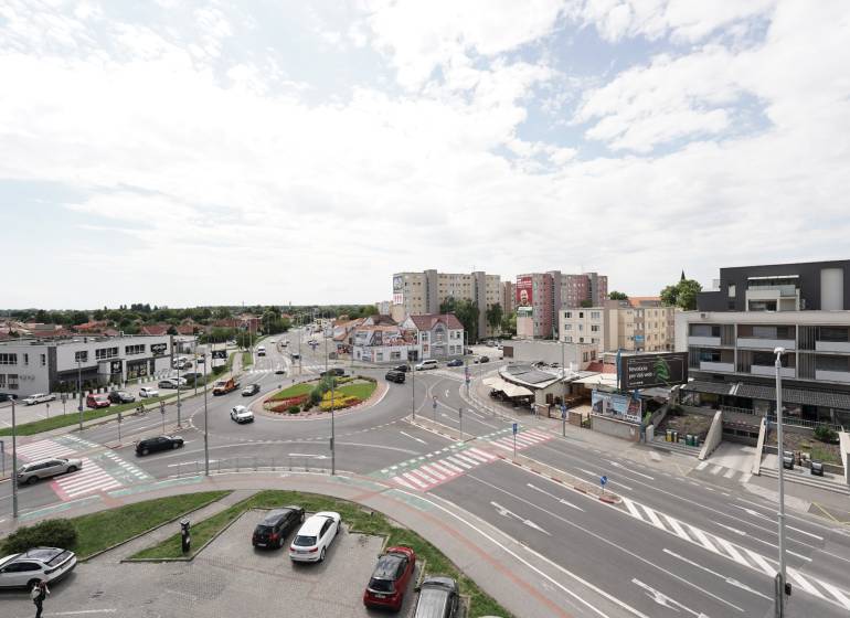 Roundabout with surroundings on Hlavná Street in Dunajská Streda, movement of cars, buildings, sky.