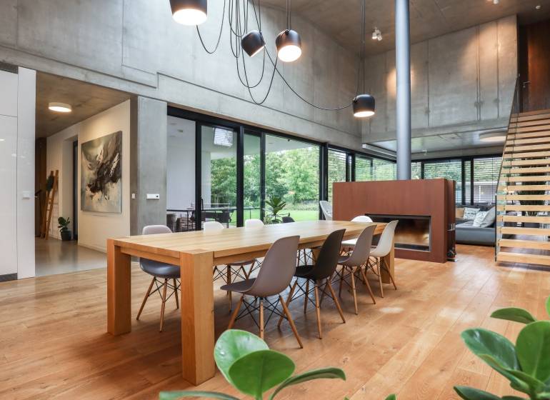 Dining room in a family house with a large wooden table, fireplace, and modern lighting.