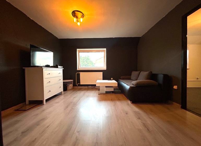 Living room in a 4-room apartment with a black couch and a white sideboard.