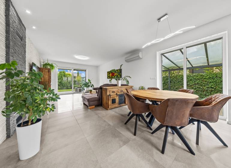 Interior of a family house with a dining area, leather chairs, and a view of the garden.