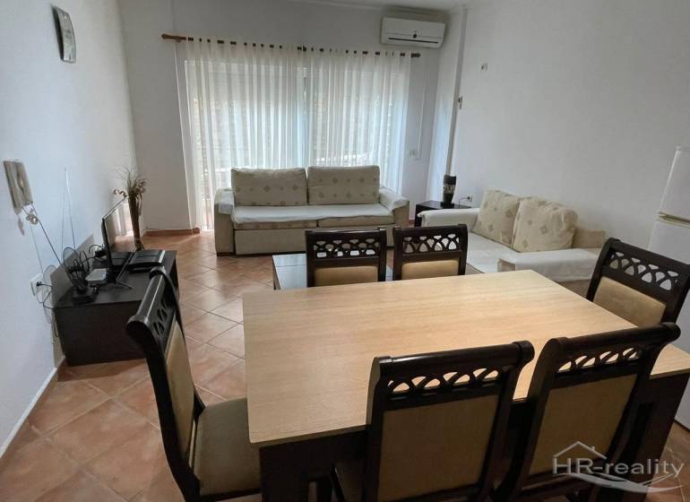 Interior of a holiday apartment with a dining table, comfortable sofas, and a television.