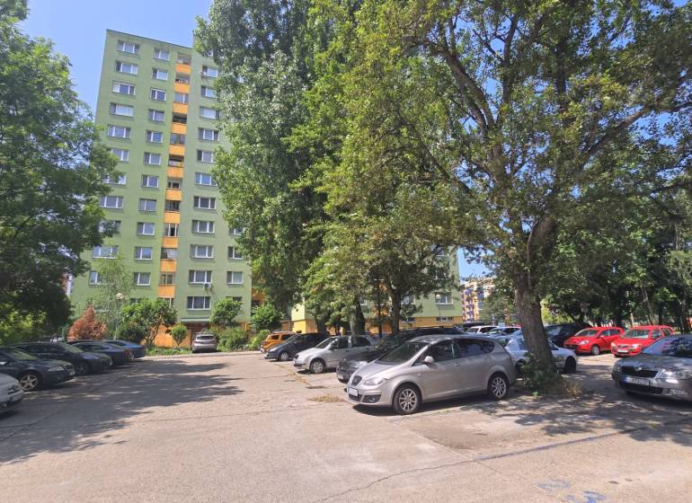 Parking lot in Bratislava - Petržalka on Osuského Street with a view of apartment buildings and greenery.