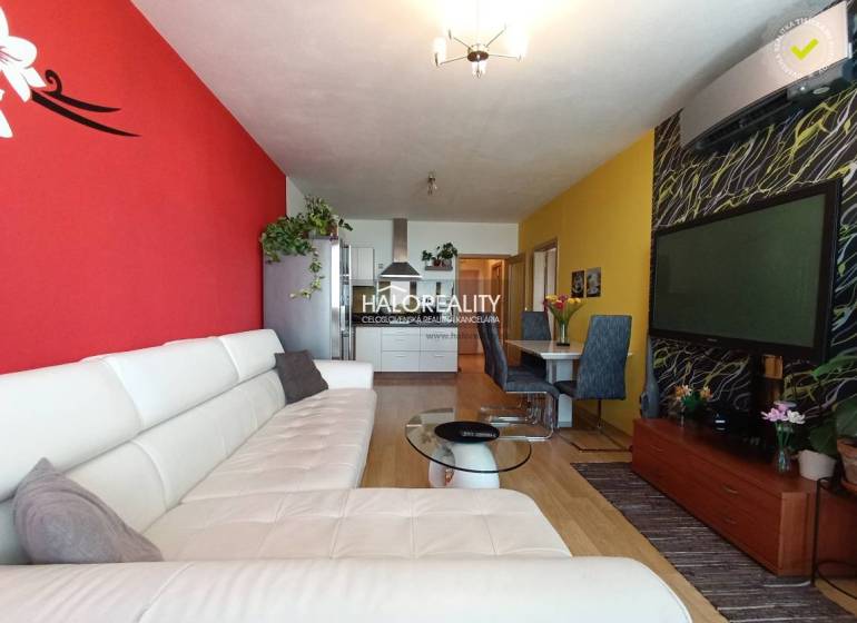 Living room with a white couch, decorative walls, and a dining table in a two-room apartment.