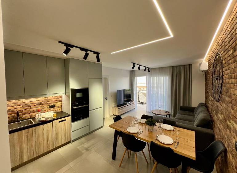 Living room with kitchen in a holiday apartment. Brick wall, dining table, and comfortable sofa.