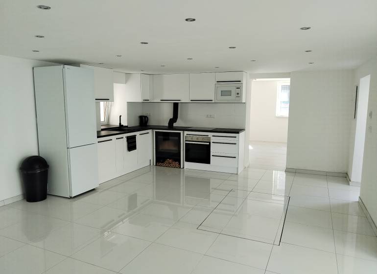 A kitchen in a family house with built-in appliances and glossy tiles.