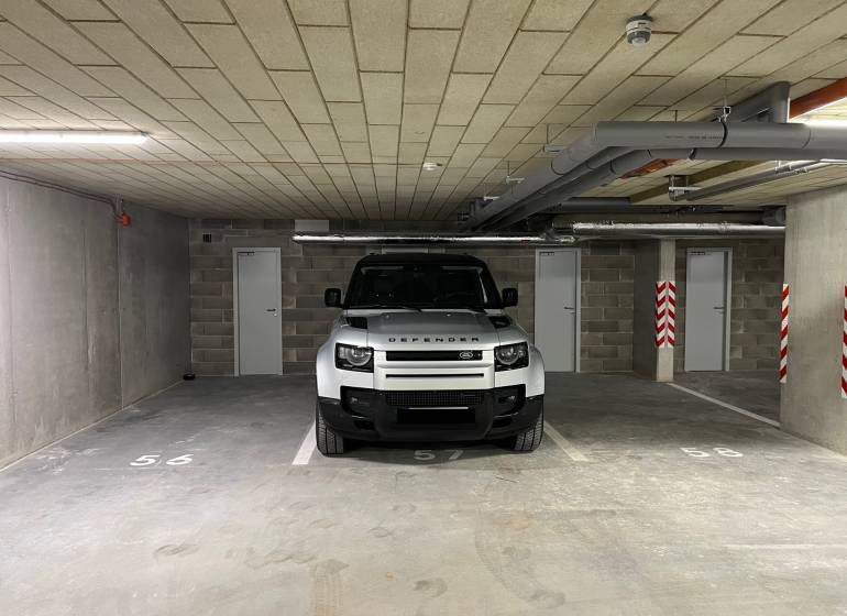 A car parking in a garage with doors and numbering on the floor.