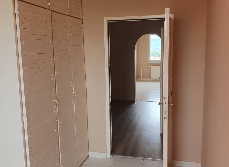 Interior of a 3-room apartment with tiles, a coat rack wall, and a passage to another room.