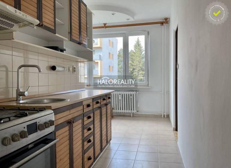 A kitchen in a 3-room apartment with a wooden cabinet, stove, and a window with a radiator.
