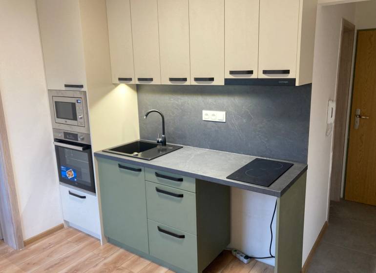 A kitchen in a 3-room apartment with a combination stove and gray cabinets.