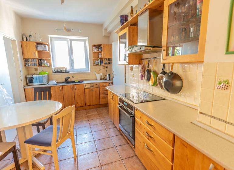 A kitchen in a 4-room apartment with wooden cabinets, a table, and ceramic tiles.