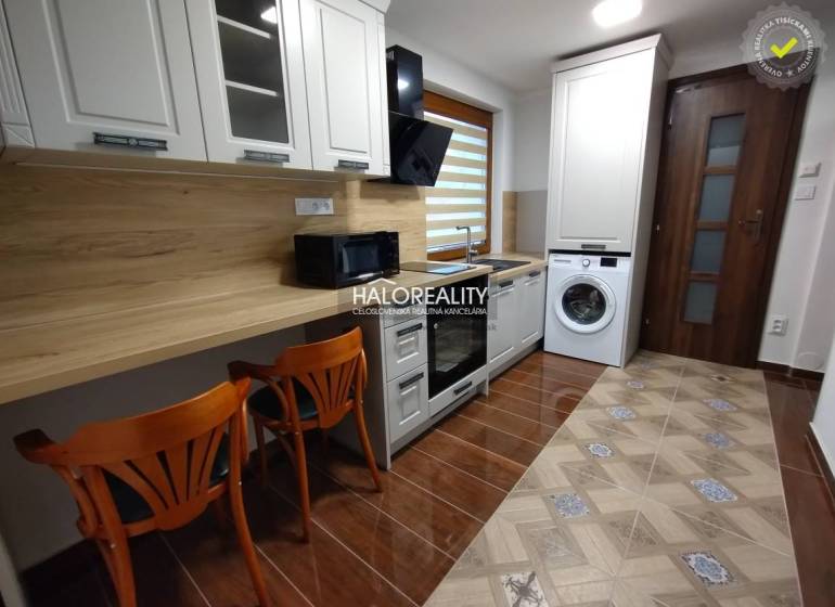 Studio apartment with a kitchenette, washing machine, and wooden chairs.