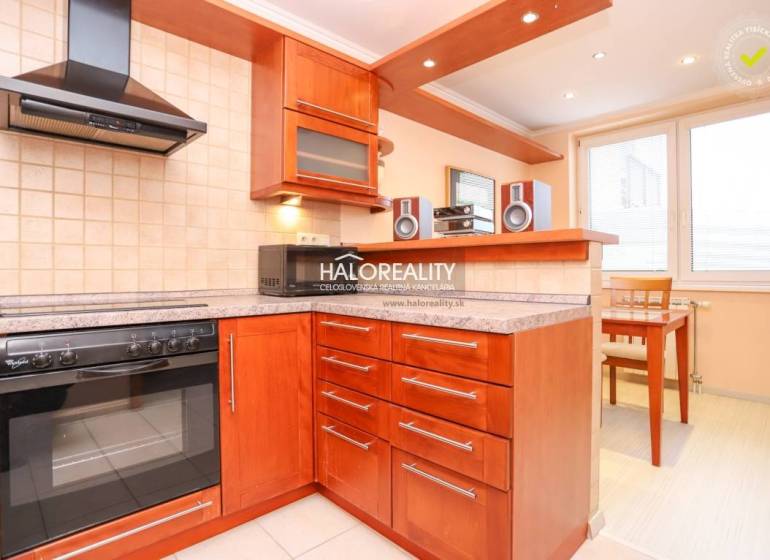 A kitchen in a 2-room apartment with a wooden kitchen unit, stove, extractor hood, and dining area.