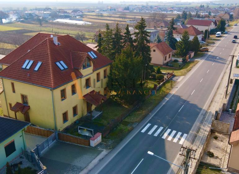 A building on Chrabrany Street in Topoľčany, surrounded by houses and trees, by the main road.