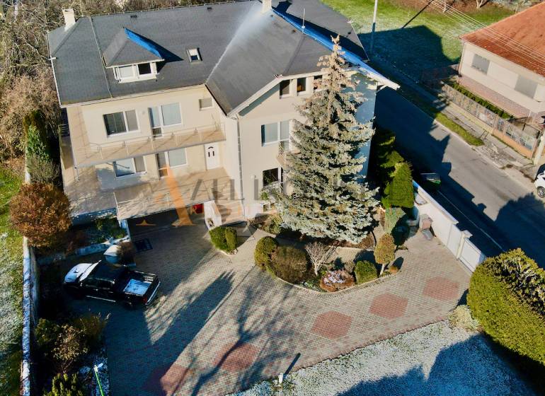 A villa on Športovcov in Topoľčany with two cars and a large garden.