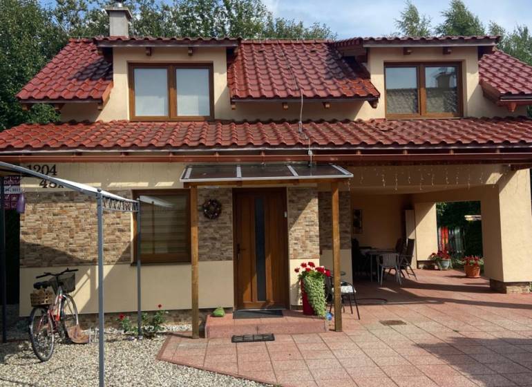 A family house on Liptovská Ondašová in Liptovský Mikuláš with a red roof and a garden seating area.