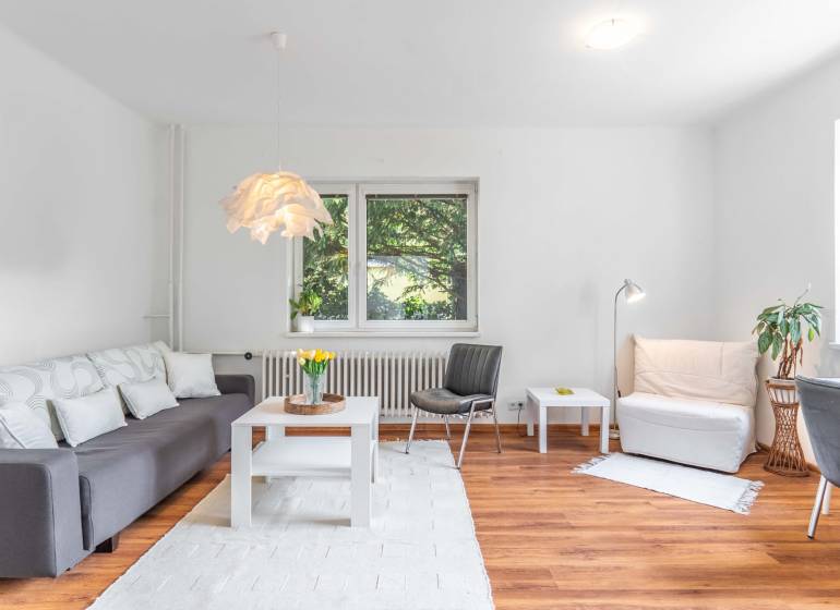Living room of a two-room apartment with a sofa and wooden floor, light decoration.
