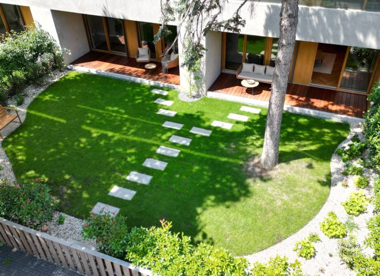 Garden terrace of a 4-room apartment with a lawn and wooden furniture.