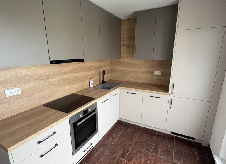 A kitchen in a 2-room apartment with wooden cabinets and dark tiles.