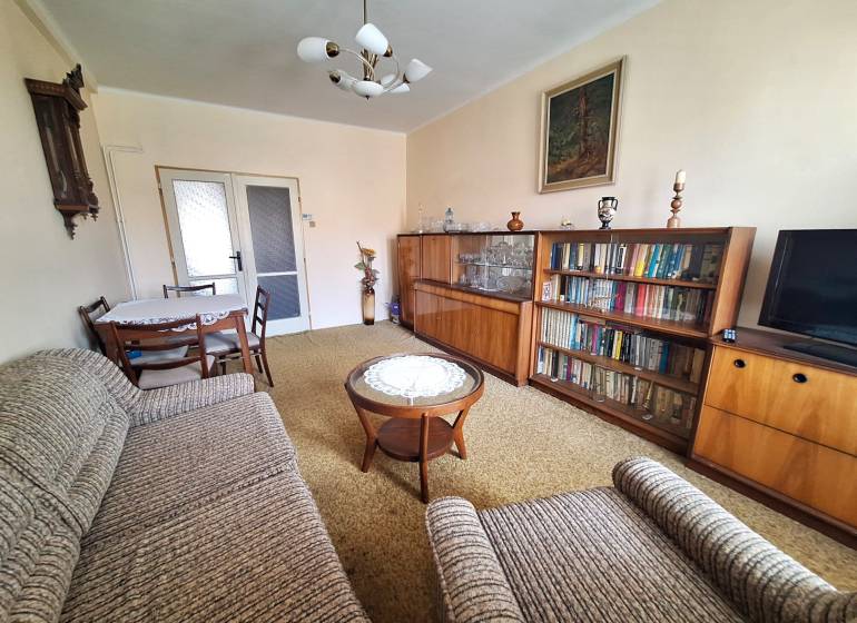 Living room in a 2-room apartment with a bookshelf, a sofa set, and a table with chairs.