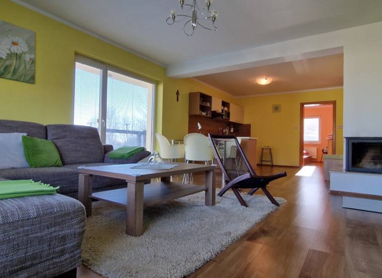 Living room in a holiday apartment with a sofa, table, and kitchenette.