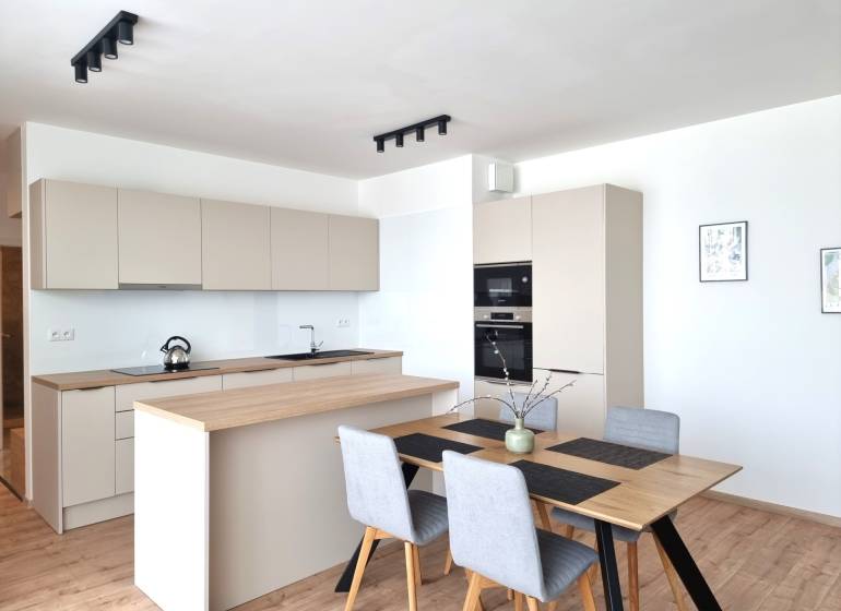 A kitchen in a 3-room apartment with a wooden table and modern appliances.