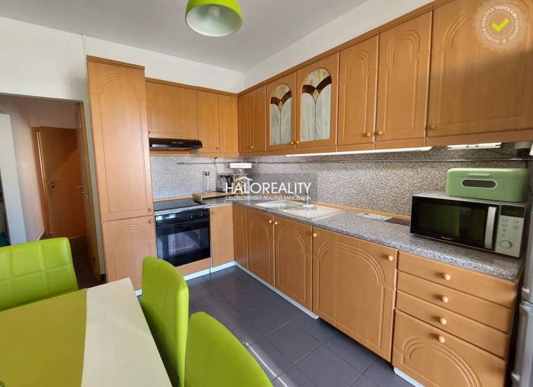 A kitchen in a 3-room apartment with a wooden cabinet and green chairs.