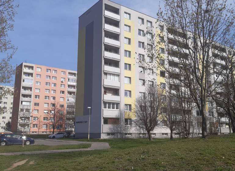 An apartment building in Trnava surrounded by trees with parking spaces, suitable for a 3-room apartment.
