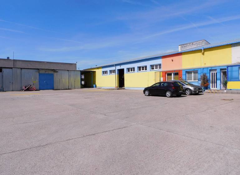 Colorful warehouse and hall buildings in Trnava with a parking lot and cars.
