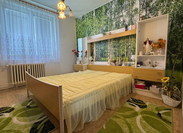 A bedroom in a three-room apartment with floral decorations and a forest wallpaper on the wall.