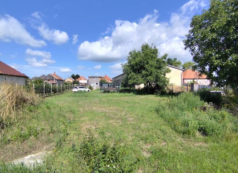 Plots - housing in Jelšovce with a view of the surrounding houses and blue sky.