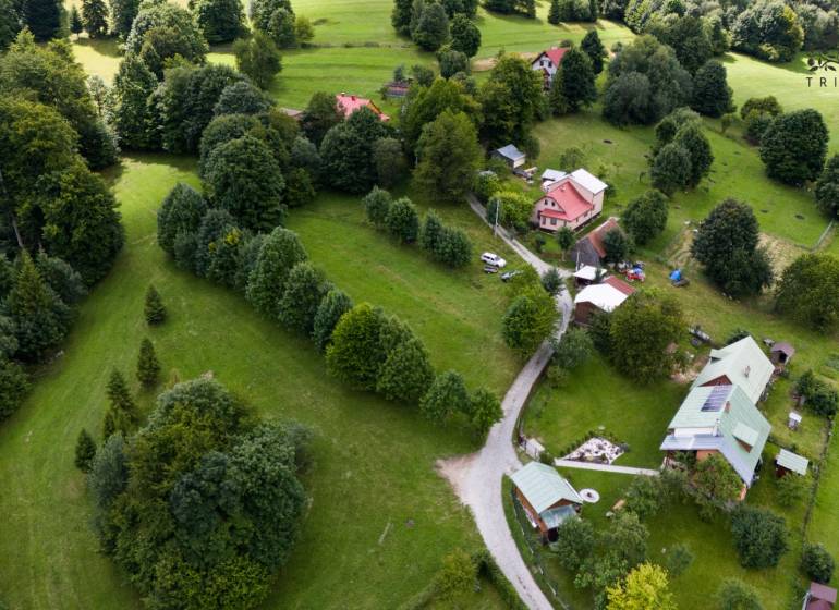 Aerial view of recreational plots in Oščadnica surrounded by dense greenery and houses.