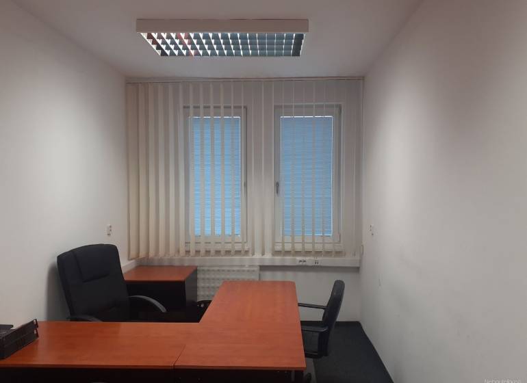 Offices with desks, black chairs, and blinds on the windows.