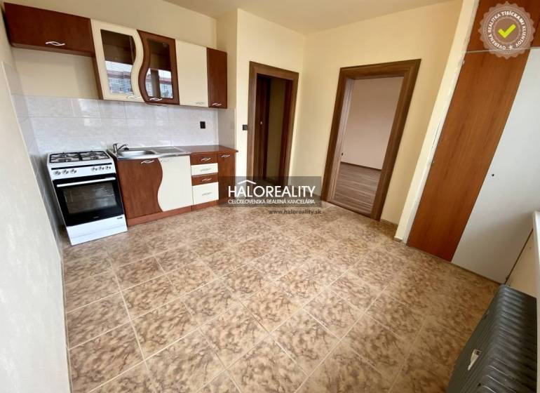 A kitchen with a gas stove and a sink in a studio apartment, with ceramic tiles.